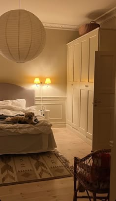 a dog laying on a bed in a room with two lamps hanging from the ceiling