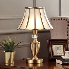 a table lamp sitting on top of a wooden desk next to a potted plant