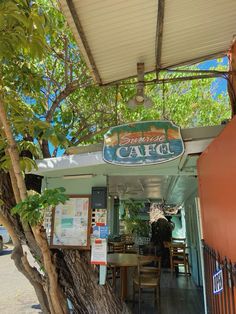 the outside of a cafe with tables and chairs under a canopy over it's entrance