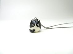 a small black and white dog necklace on a silver chain