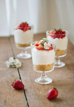 three small desserts with strawberries on the table