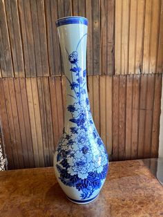 a blue and white vase sitting on top of a wooden table next to a wall