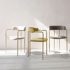 three chairs in different colors and sizes against a white wall