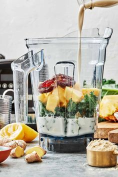 a blender filled with fruit and vegetables on top of a counter next to other ingredients