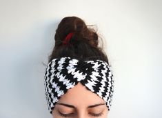 a woman with her eyes closed wearing a black and white knitted headband over her face