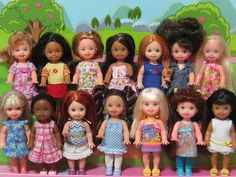 a group of dolls standing next to each other in front of a green field with trees