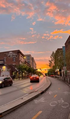 cars are driving down the street at sunset