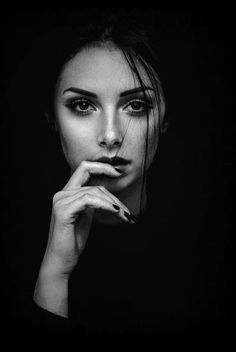 a black and white photo of a woman with her hand on her chin looking at the camera