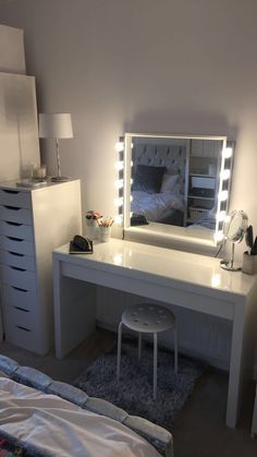 a white vanity with lights on it in a bedroom