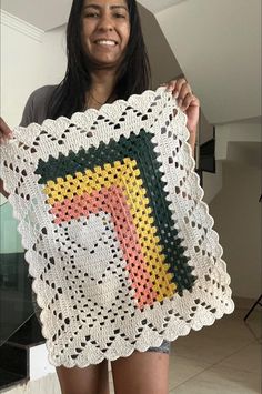 a woman holding up a crocheted square with an image of a cat on it