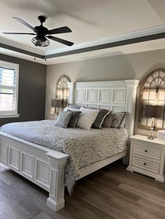 a large white bed sitting inside of a bedroom next to a dresser and window on top of a hard wood floor