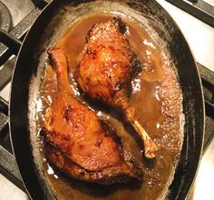 two pieces of chicken are in a pan on the stove with brown gravy