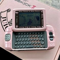 a pink and black cell phone sitting on top of a table next to a book