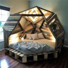 a bed made out of wooden pallets with lights on top and pillows in the middle