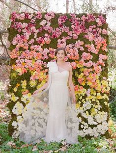 a woman standing in front of a flower covered wall