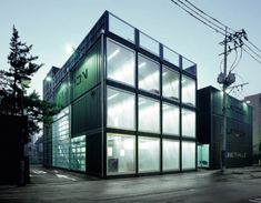 people are walking in front of a building with glass panels on the side and an airplane flying overhead