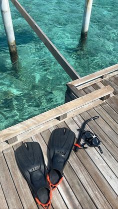 two pairs of flip flops sitting on top of a wooden dock next to the ocean