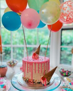 a birthday cake with ice cream and sprinkles on it, surrounded by balloons