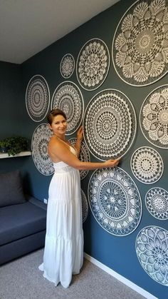 a woman standing in front of a wall with circular designs on it