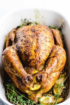 a roasted chicken in a white bowl with herbs