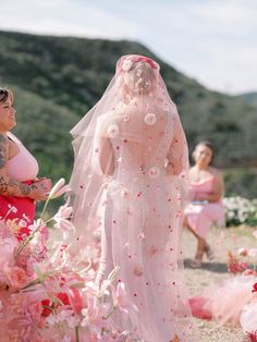 two women in pink dresses standing next to each other and one woman with tattoos on her arm