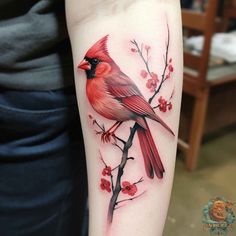 a red bird sitting on top of a tree branch with berries in the foreground