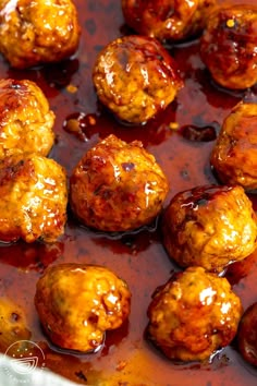 meatballs covered in sauce sitting on top of a pan