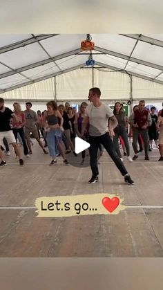 a group of people are dancing in a tent with the words let's go