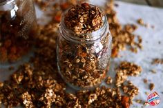 a jar filled with granola sitting on top of a white table next to two glass jars