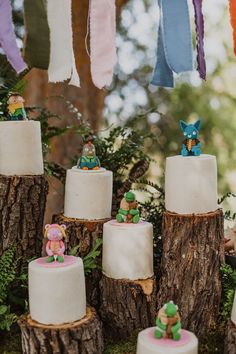 there are many small cakes on the tree stumps that have been decorated with little figurines