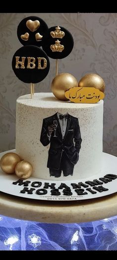 a white cake with gold decorations on top and a photo of a man in a tuxedo