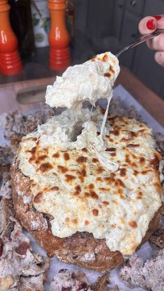 a person is dipping cheese on top of a pizza