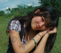 a woman sitting in the grass with her hands on her head