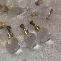 three clear glass knobs with gold accents on a white surface next to plastic bags