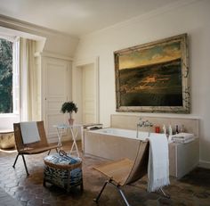 a bath room with a tub a chair and a painting