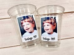 two plastic cups with pictures on them sitting on a wooden table next to each other