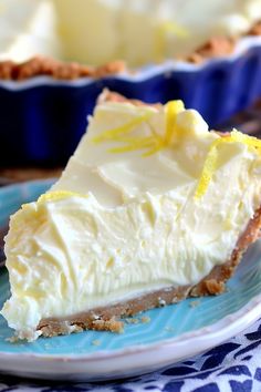 a slice of lemon pie on a blue and white plate next to another pie in the background