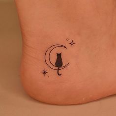 a black cat sitting on the moon with stars around its neck tattooing it's foot