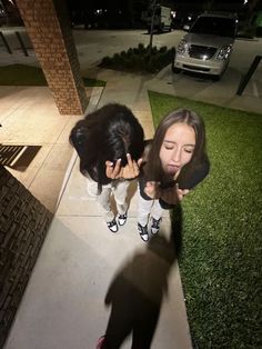 two girls standing on the sidewalk looking at something