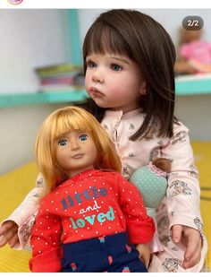 two dolls sitting next to each other on a table