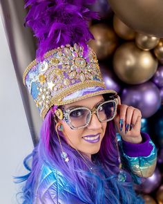 a woman with purple hair and sunglasses is wearing a tiara in front of balloons