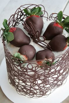 chocolate covered strawberries in a wire basket on top of a white cake plate with green leaves