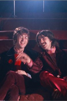 two young men sitting next to each other in front of a red screen with lights on