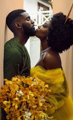 a man and woman kissing each other with flowers in front of them