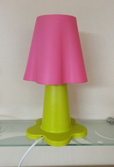 a pink and yellow lamp sitting on top of a glass shelf