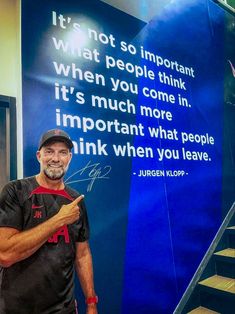 a man standing in front of a blue wall with a quote on it that reads, it's not so important when you think it're