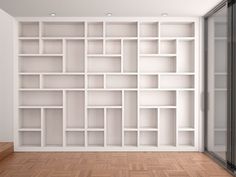 an empty white bookcase in front of a wooden floor and wall with glass doors