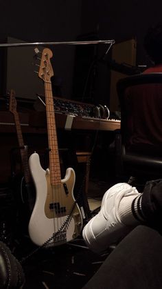 an electric bass guitar sitting on the floor next to a person's legs and feet