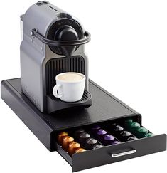 an espresso machine with its drawer open and coffee cups in the bottom compartment