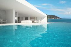 an empty swimming pool next to a large white building with a view of the ocean